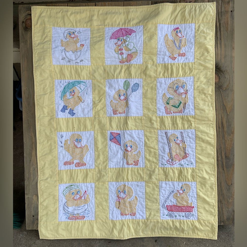 Vintage baby quilt with cross-stitch ducks in many activities.
